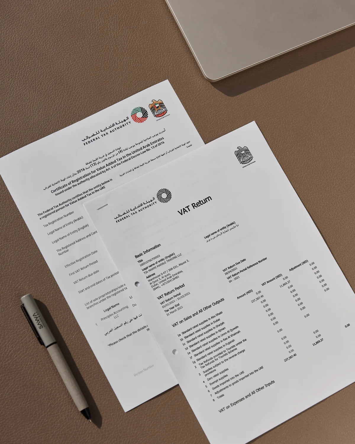 A UAE VAT return and TRN certificate on a desk